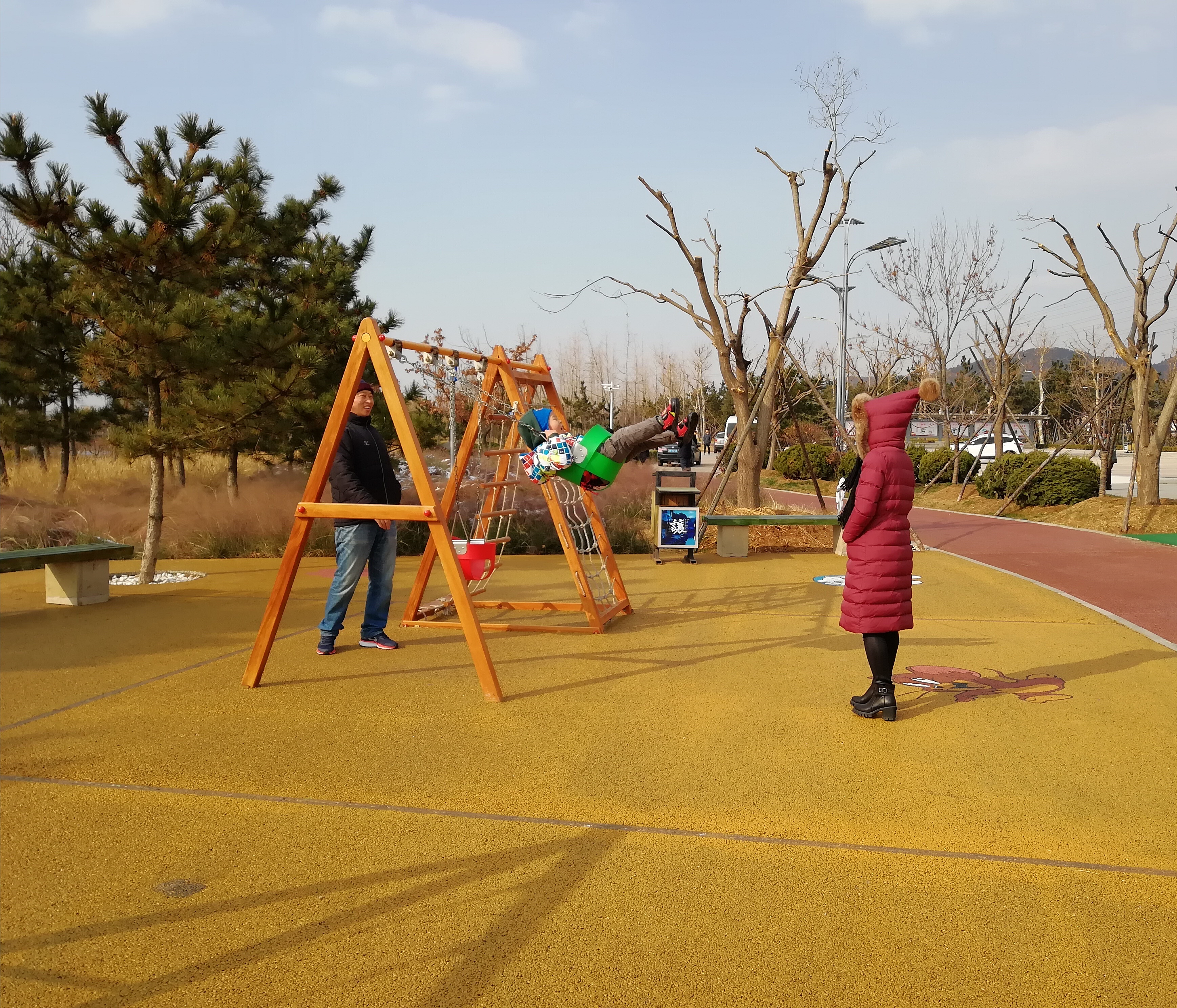 在羊亭公园，一对夫妻陪孩子荡秋千