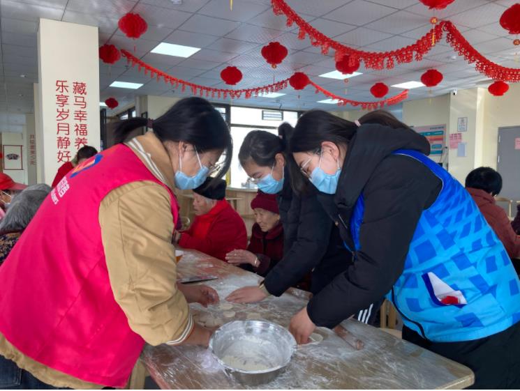 养老服务中心工作人员和老人包饺子迎新春。