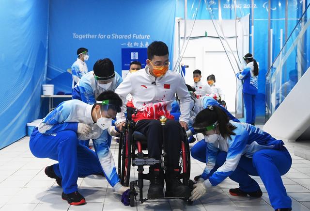 3月6日，志愿者赛前为中国队选手陈建新清洁轮椅。新华社记者 任超 摄

