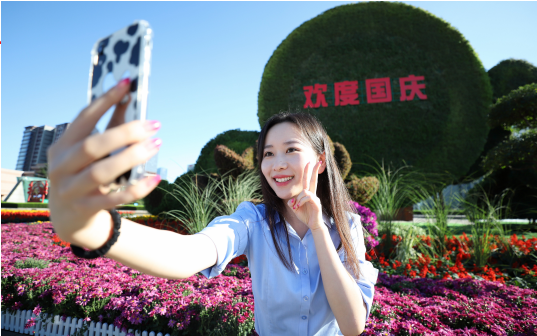 市民在市民文化广场“欢度国庆”花坛前拍照留念。