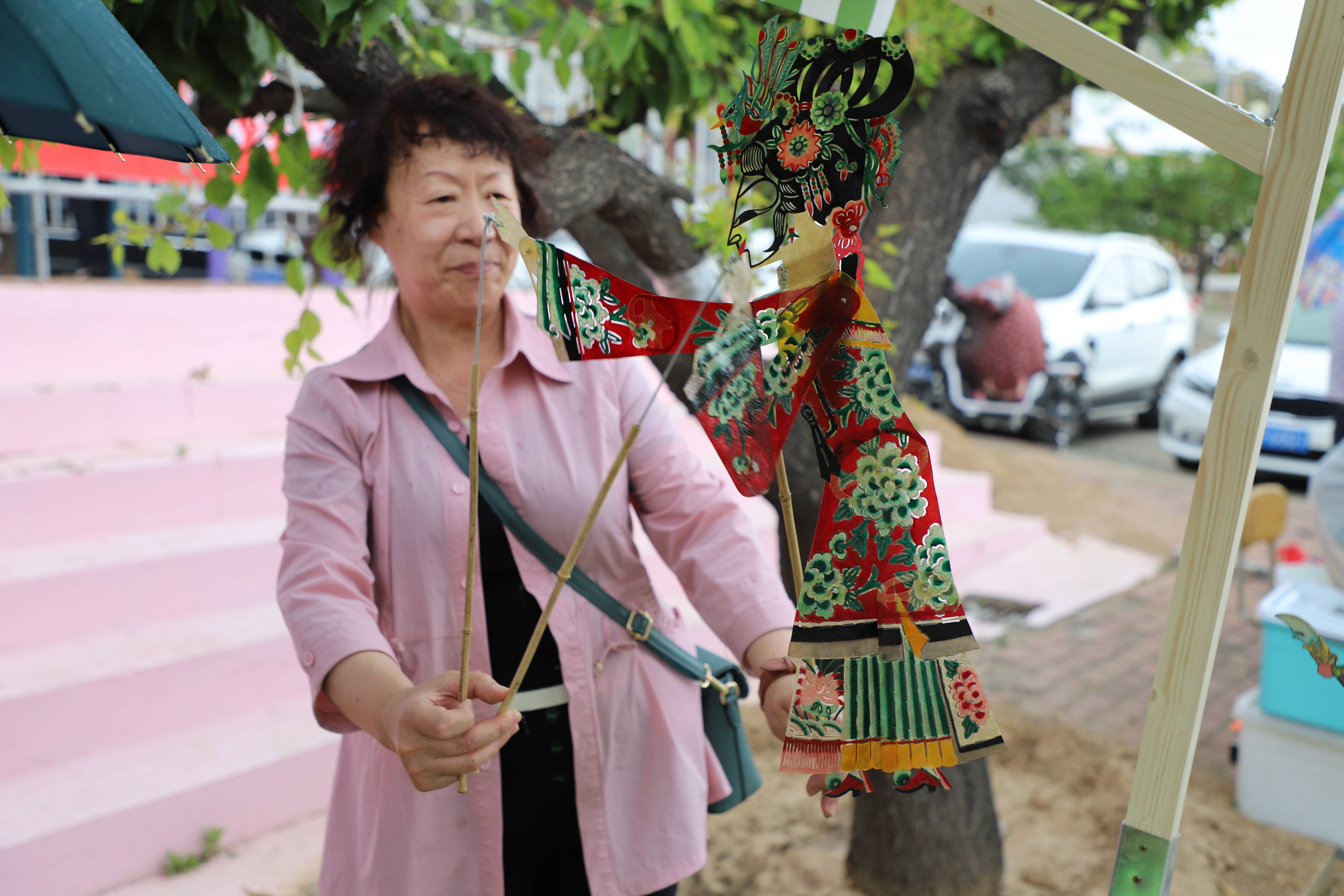 在毛家山非遗市集上，游客舞动人偶，感受皮影的乐趣。