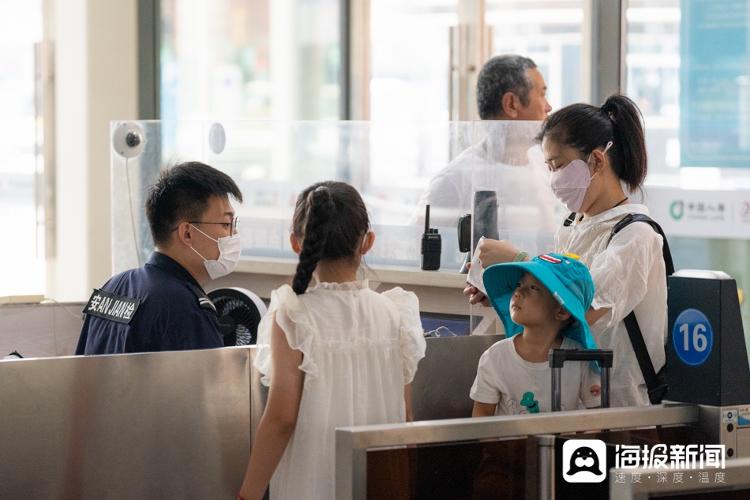 图：济南火车站工作人员在人工检票口检查进站儿童的身份证明。（海报新闻记者 毕胜 摄）