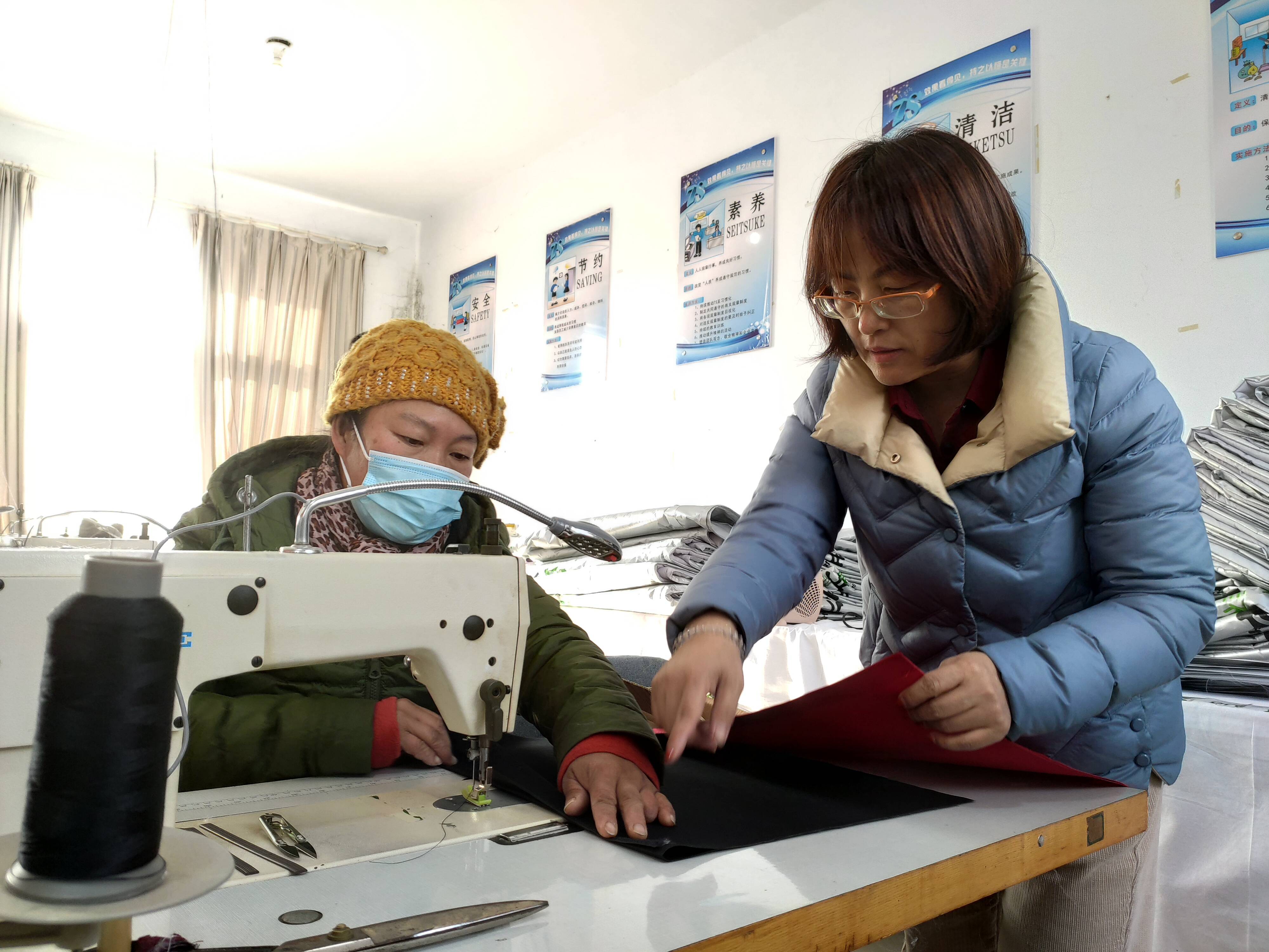 樊本香(右)与惠民工厂里的村民一起讨论新订单的制作细节。