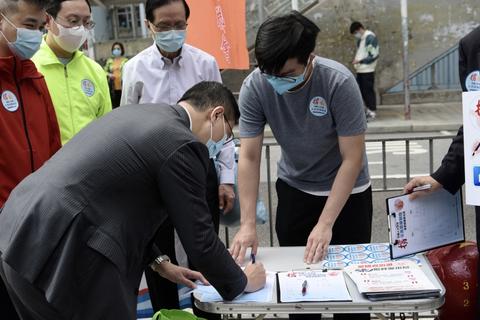 图为香港教育局局长杨润雄签名支持完善选举制度