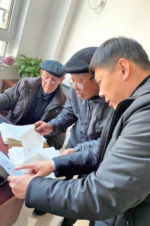 陈志超(右一)到村委查找当年的倒包合同。