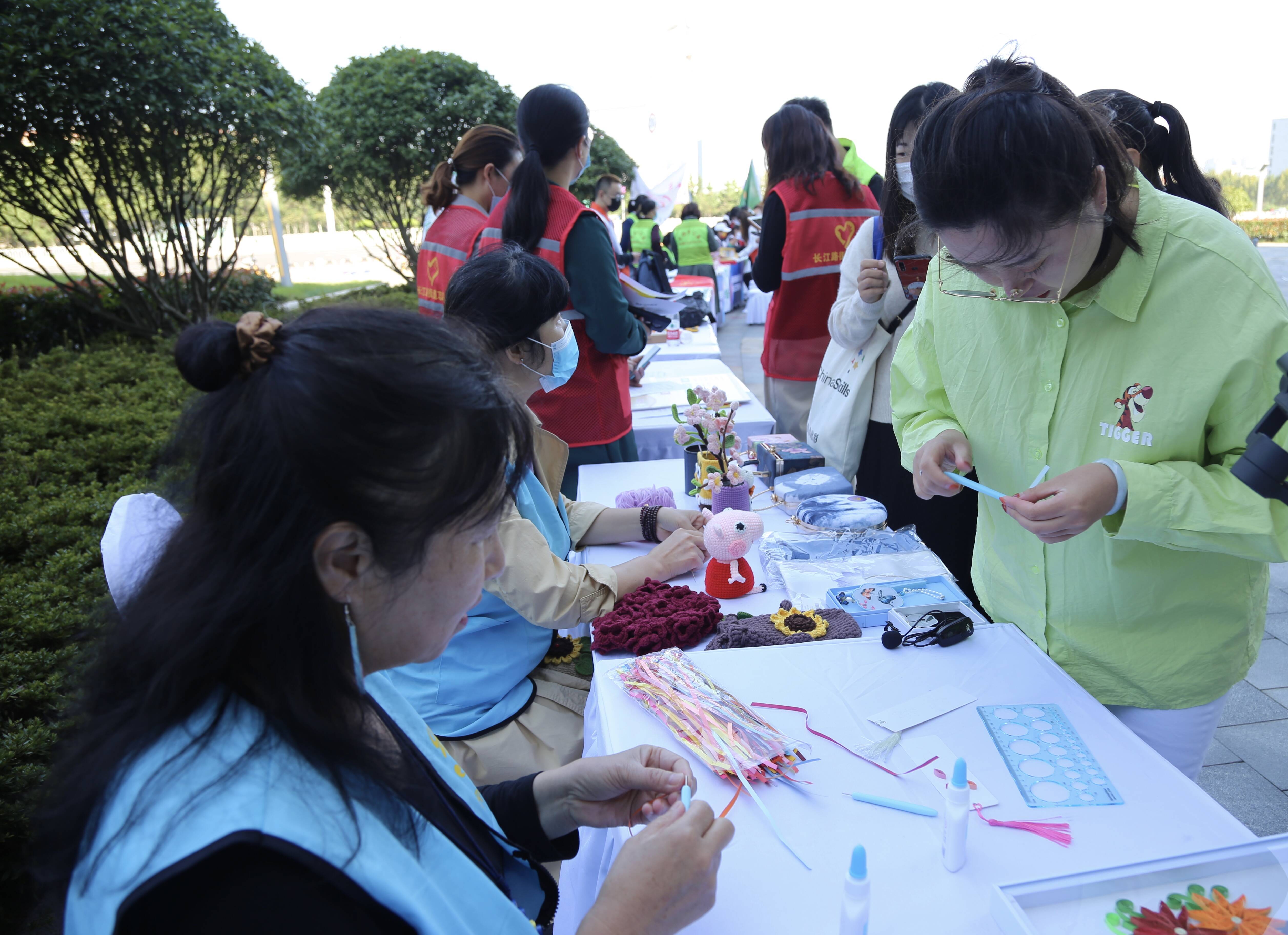 志愿服务大集上，志愿者教授居民制作彩纸手工艺品。