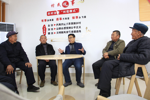 乡村振兴服务队队员王晓明（中）与村民议事会成员一起讨论村务。