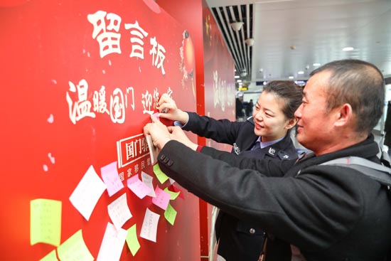 1月17日，青岛机场出入境边防检查站民警协助旅客粘贴“家国情怀”留言板卡片。
