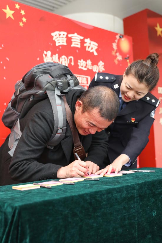 1月17日，青岛机场出入境边防检查站民警协助旅客填写“家国情怀”留言板卡片。