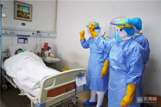 邹平市人民医院新型冠状病毒感染的肺炎隔离区的医生和护士在查房结束后，给已经确诊病毒感染的患者加油