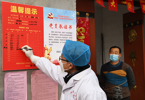 2月2日，在店子镇尚河村，卫生院公卫办工作人员在隔离观察的武汉返乡人员门口填写所测量得体温状况。