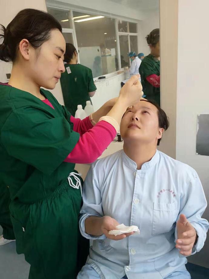 淄博赴湖北援助医疗队员相互用生理盐水洗眼睛。