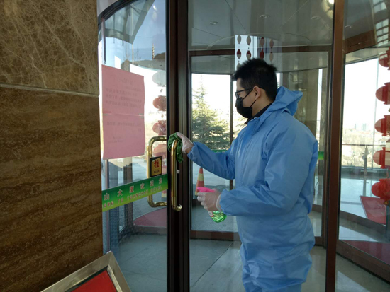 原山大厦工作人员对门禁口把手进行消毒杀菌。