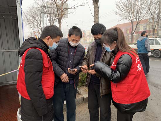 2月21日，在G220防疫检查站，利津县北宋镇青年突击队队员帮助返乡人员填写通行证信息