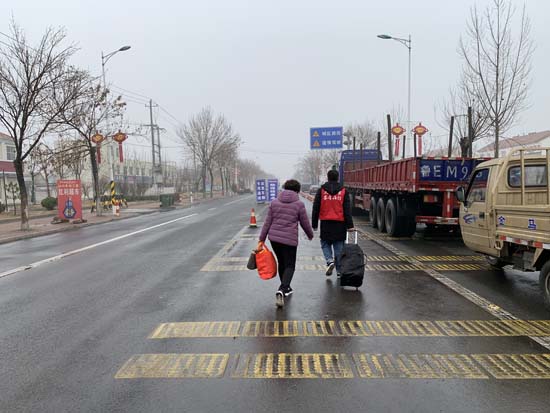 2月21日，在G220防疫检查站，北宋镇青年突击队队员帮助返乡人员运送行李
