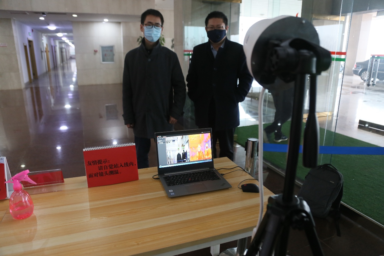 2月21日上午，在临淄区人民政府大厅内，进出人员在设备前进行体温测量。