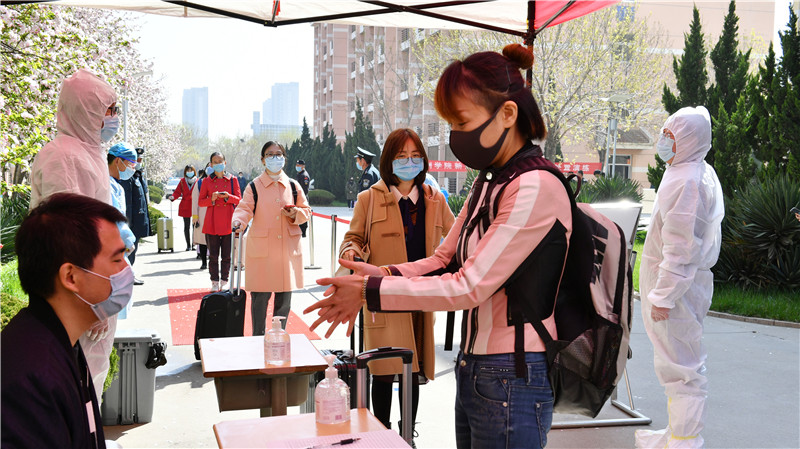 辅导员扮演的“学生”凭健康码、学生证在信息登记处登记信息，并进行手部消毒。