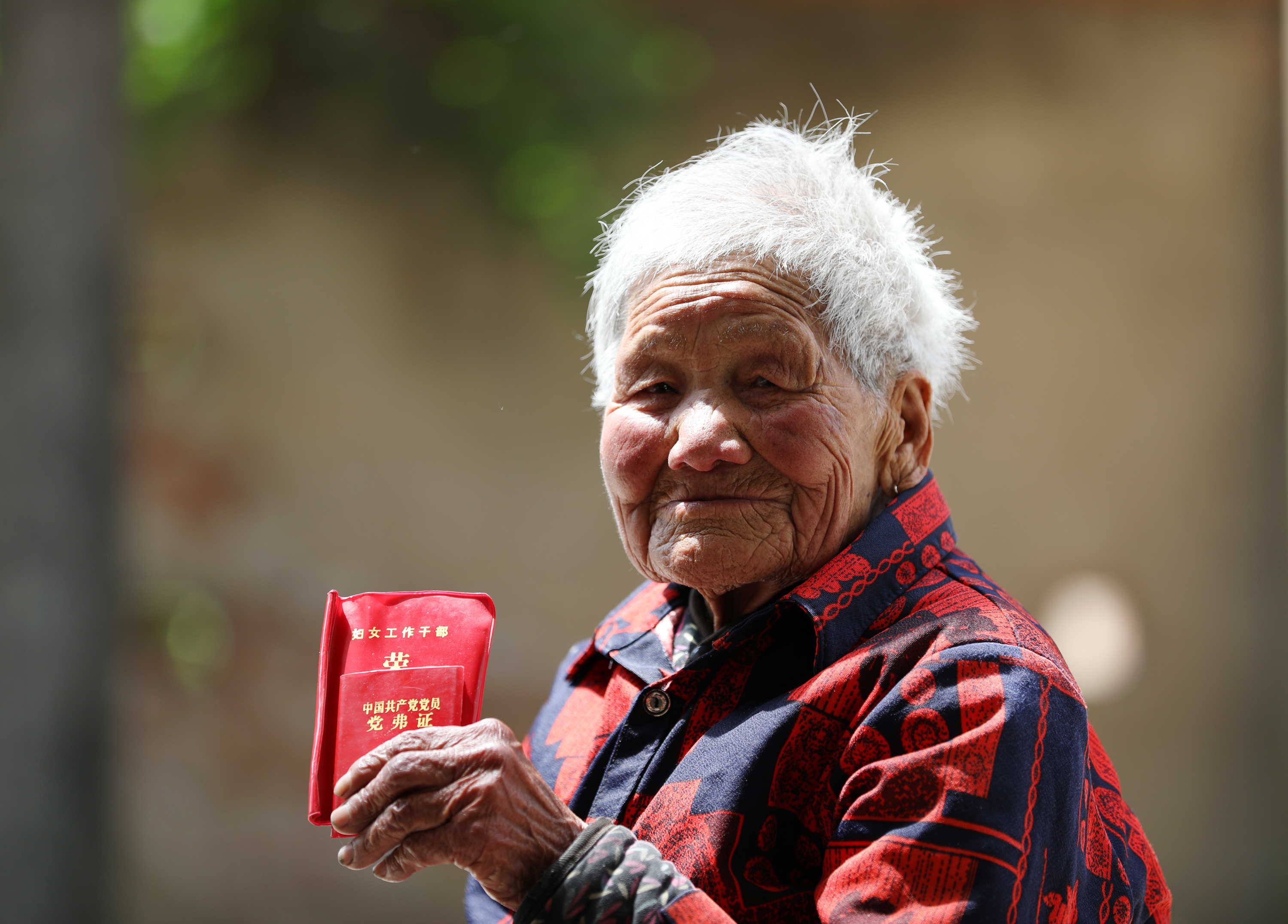 5月17日，郯城街道北墩村建国前老党员李秀英展示党费证和妇女工作荣誉证书。（张春雷摄）