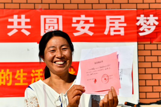 在菏泽市鄄城县旧城镇六合社区（三合村村台），王庄村村民在展示自己的选房确认单（2020年9月20日摄）。新华社记者 郭绪雷 摄