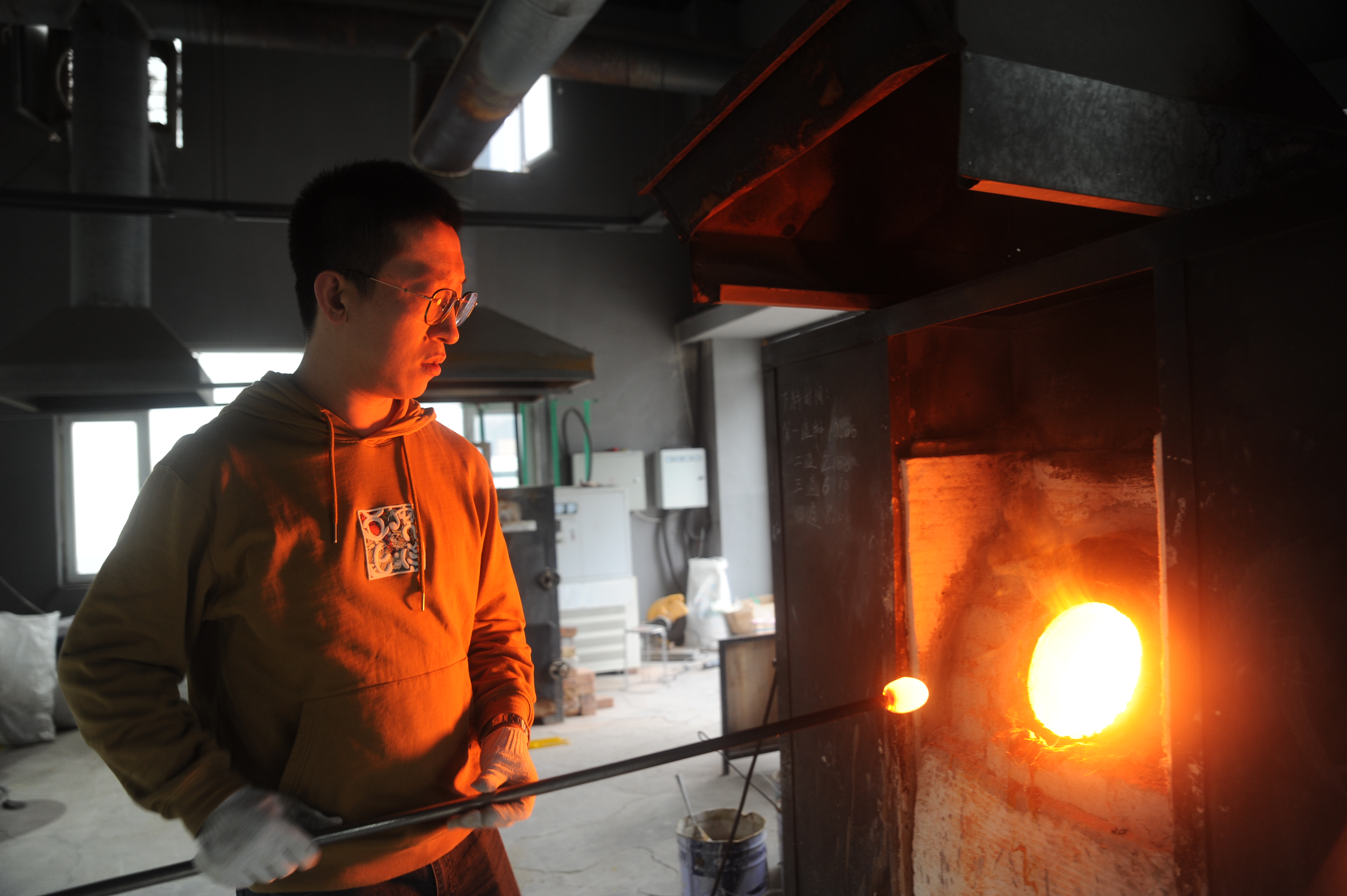 徐磊从窑炉里取出琉璃色料。