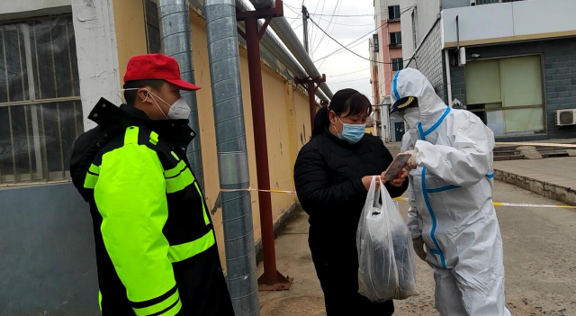 图为张三伟与郭守成在老旧小区门前执勤，查验居民“两码”、核酸检测情况