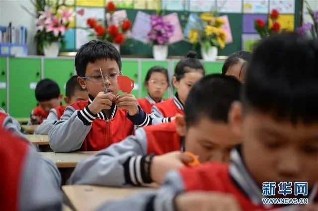新华社资料图：小学生在校内课后服务课堂上练习剪纸。