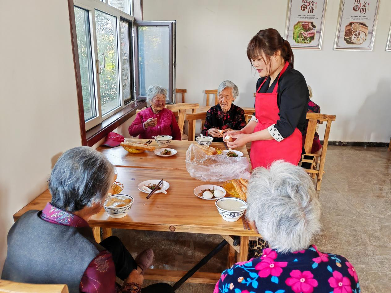 图为四门洞村志愿者在暖心食堂为老人提供志愿服务。