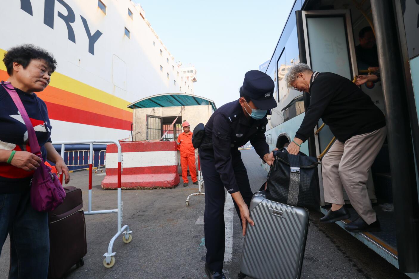 10月25日，在青岛邮轮母港，山东出入境边防检查总站青岛边检站民警协助出境旅客登轮。摄影：钱程