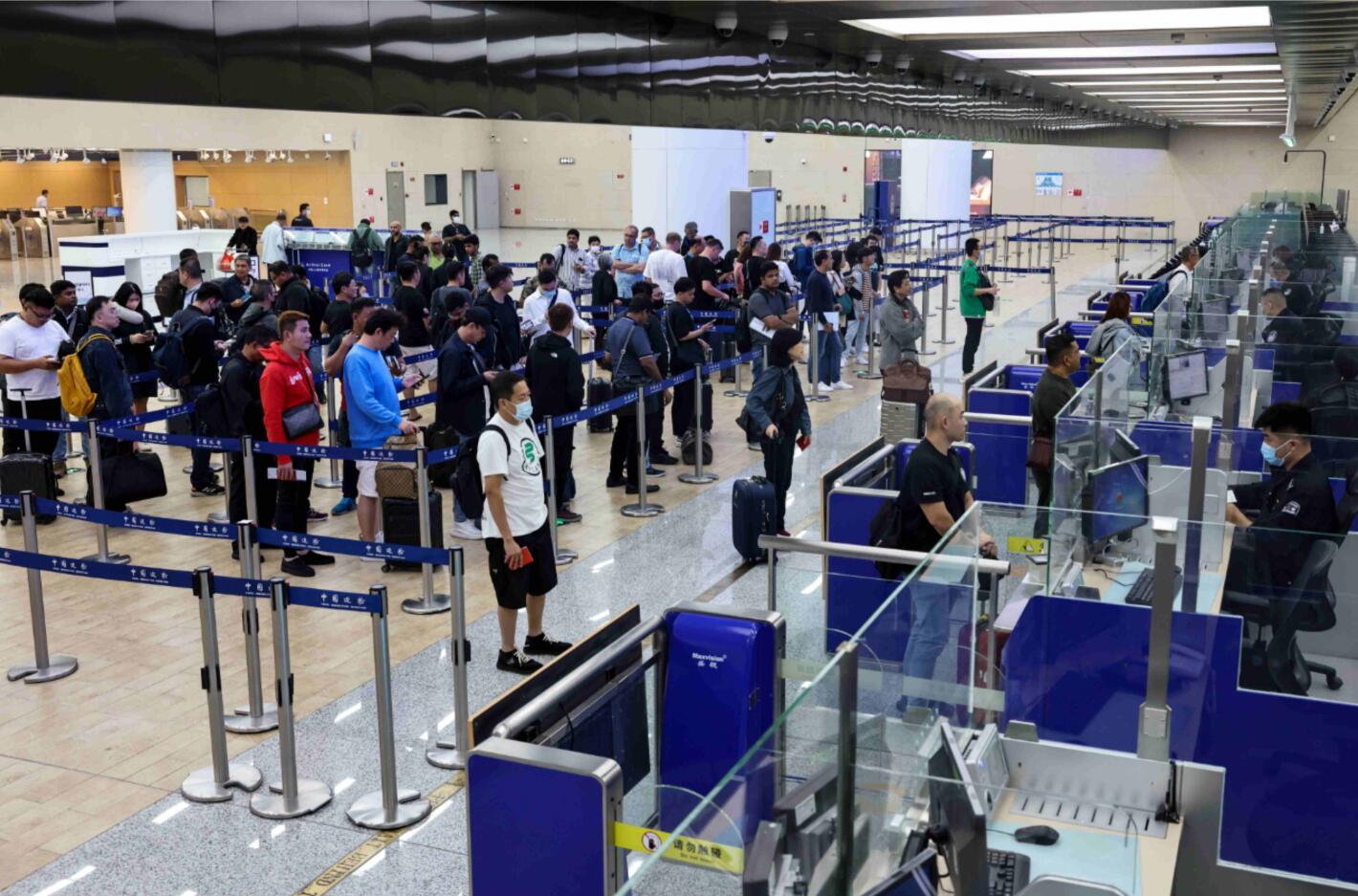 10月25日，中外旅客正在青岛胶东国际机场入境大厅等待边防检查。摄影：钱程