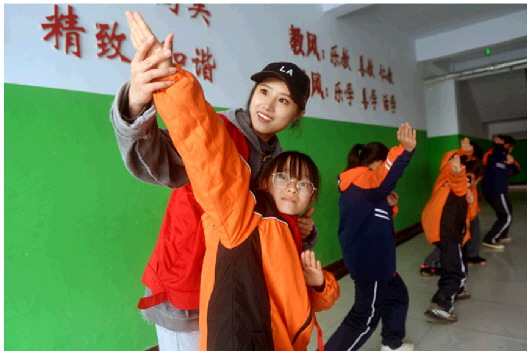 在西小王镇中心小学教学楼大厅里，年轻的志愿者教孩子们跳起欢快的街舞。