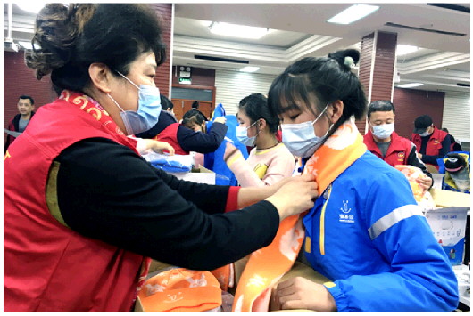 志愿者将包括全套冬衣在内的“温暖包”送到帮扶儿童的手中。
