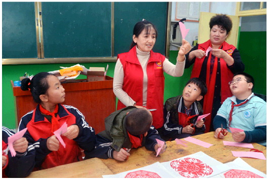 在西小王镇中心小学教室里，当地非遗传承人方秀岭（右四）在教学生们剪纸。